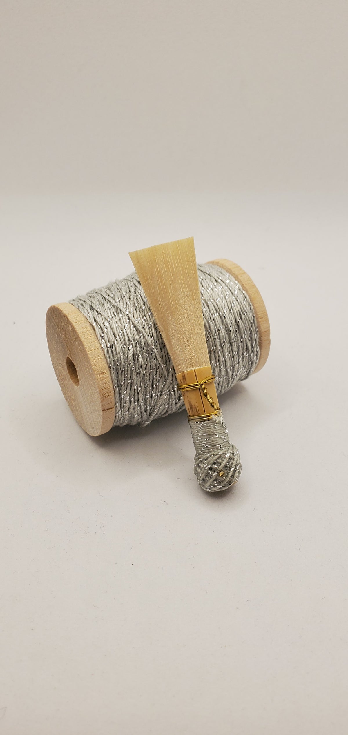 A handcrafted, unfinished bassoon blank with sparkling silver thread, displayed on a white background.